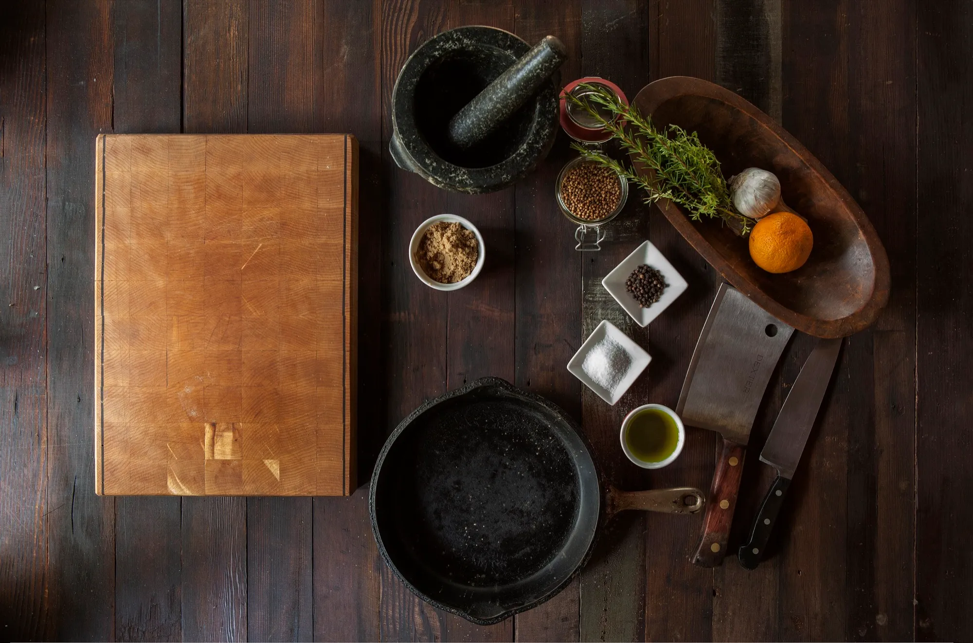 Puesto de cocina visto desde arriba, con tabla, cuchillos, especias y sartén