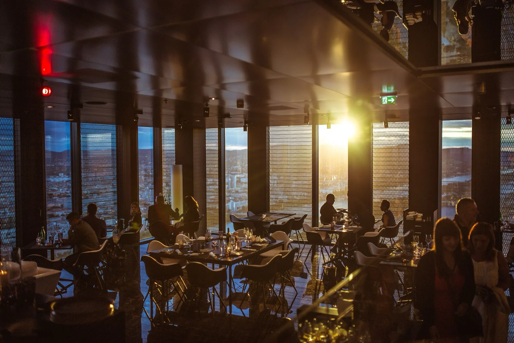 Comedor de un restaurante en altura al atardecer, con la ciudad al fondo